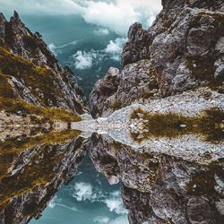 Reflection of rocks in lake against sky