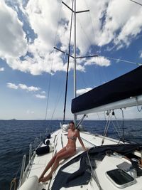 Woman sitting on sailboat in sea against sky