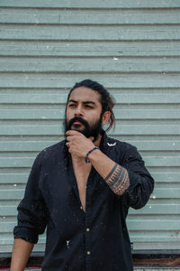 Portrait of young man standing against wall