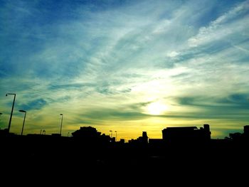 Silhouette built structures against sky at sunset