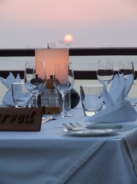 Glasses on table at restaurant against sky during sunset