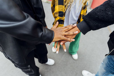 Friends stacking hands standing on footpath