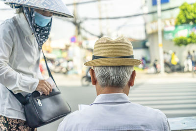 Rear view of man with umbrella on street in city