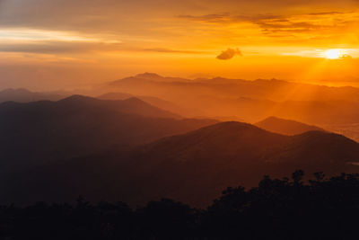 Scenic view of silhouette mountains against orange sky
