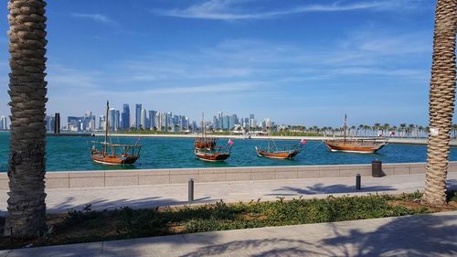 Sailboats in sea against buildings in city