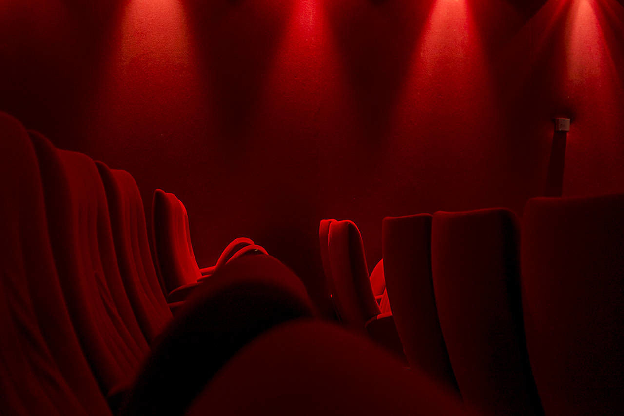 red, movie theater, arts culture and entertainment, human body part, body part, indoors, stage theater, people, unrecognizable person, film industry, seat, auditorium, lifestyles, real people, velvet, in a row, leisure activity, curtain, human leg, human foot, stage, nightlife, human limb