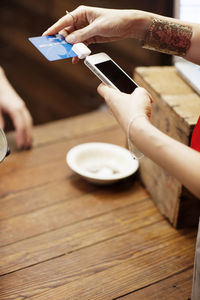 Cropped image of woman using credit card reader for paying