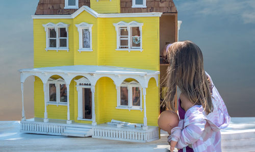 A little girl is lost in wonder as she examines this beautiful old vintage doll house