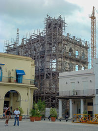 People at construction site against sky in city