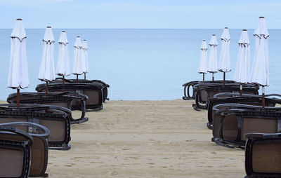 Deck chairs on beach against sky