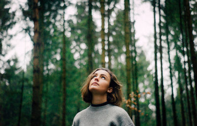 Young woman looking up in forest