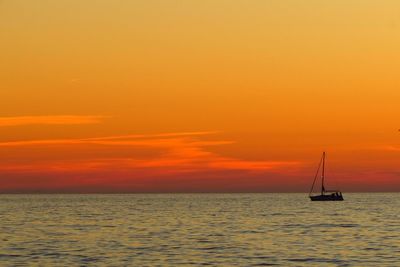 Sailboat sailing on sea against romantic sky at sunset