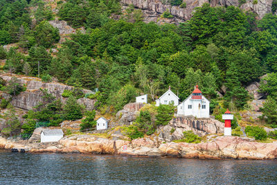 Trees and buildings by river against mountain