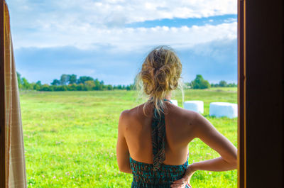 Rear view of woman standing on land against cloudy sky