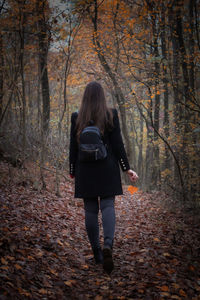 Rear view of woman walking in forest during winter