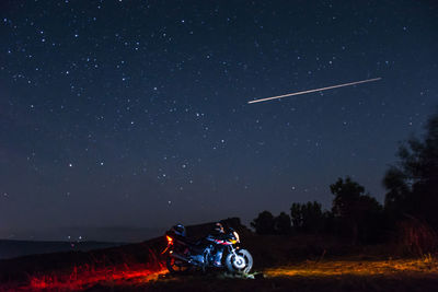 Motorcycle on field against star field at night