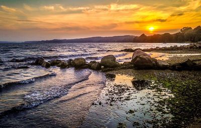 Scenic view of sea against cloudy sky during sunset