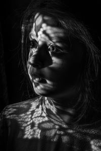 Light falling on thoughtful girl in darkroom