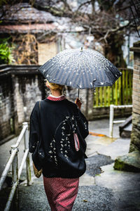 Rear view of woman with umbrella walking on street