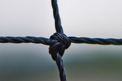 Close-up of barbed wire fence against sky