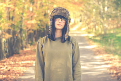 Portrait of young woman standing against trees