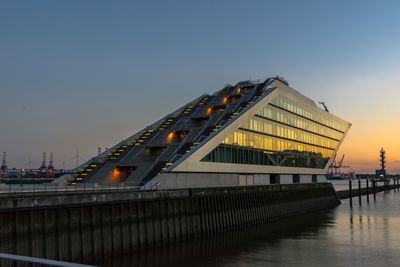 Bridge over river against sky at sunset