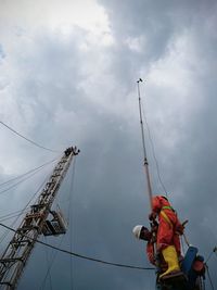 Low angle view of men working against sky