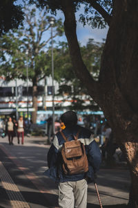 Rear view of men with backpack walking in city