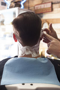 Cropped image of barber applying shaving cream on customer