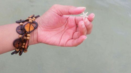 Cropped image of woman holding starfish at beach