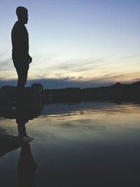 Silhouette man standing on water against sky