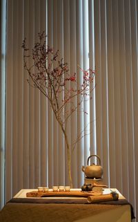 Flower vase on table against window at home