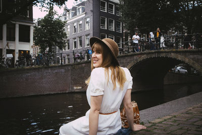 Young woman smiling while standing at canal