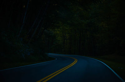 Empty road amidst trees in forest