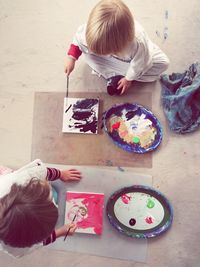 High angle view of siblings painting on papers at home