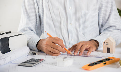 Midsection of architect working on table