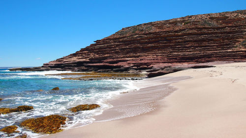 Scenic view of beach against clear blue sky