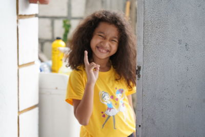 Happy woman standing against yellow wall