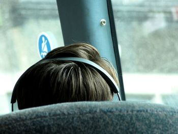 Close up of back of man's head wearing headphones relaxing on bus