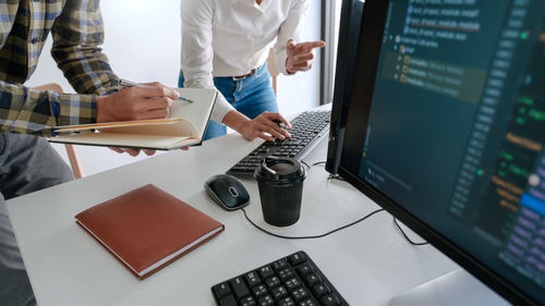 Midsection of programmers working on table