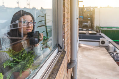 Portrait of woman looking through window