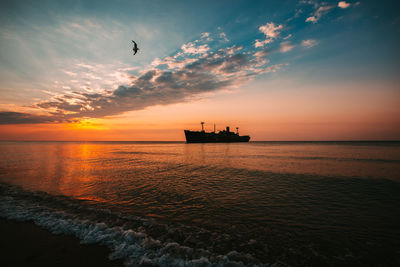 Silhouette boat in sea against sky during sunset