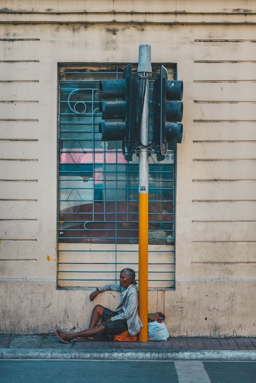 FULL LENGTH OF WOMAN SITTING ON CLOSED DOOR OF BUILDING