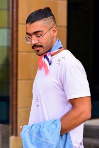 Young man looking away while standing outdoors