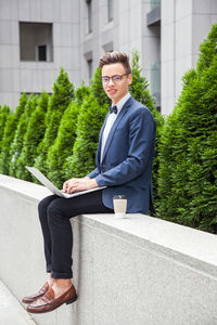 Young man sitting on wall