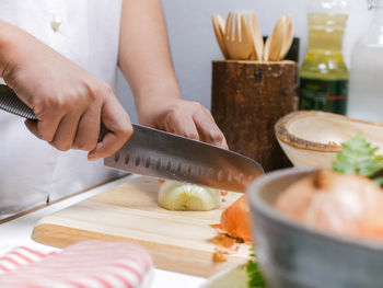 Midsection of person cutting onion on table