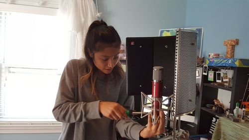 Woman repairing microphone in home