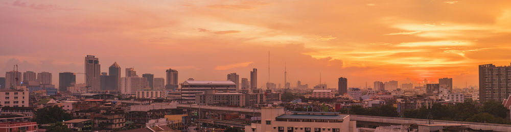 Modern buildings in city against sky during sunset