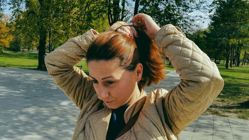 Woman adjusting hair on footpath at park