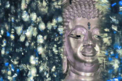 Close-up of buddha statue seen through glass